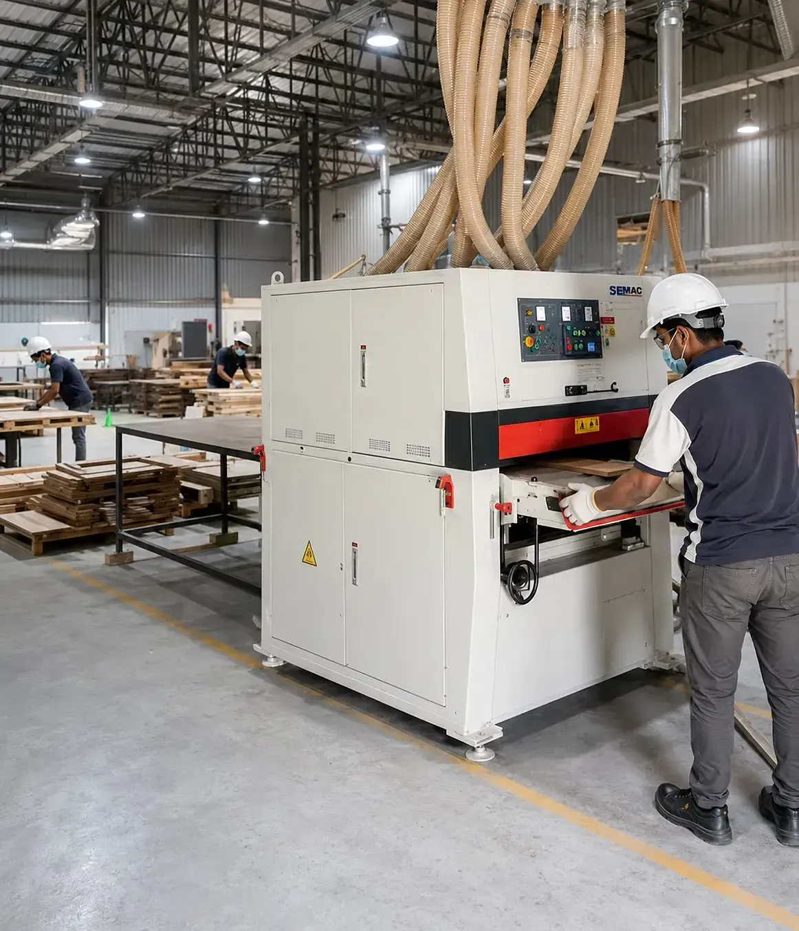 Operator running a wide-belt sander on the factory floor